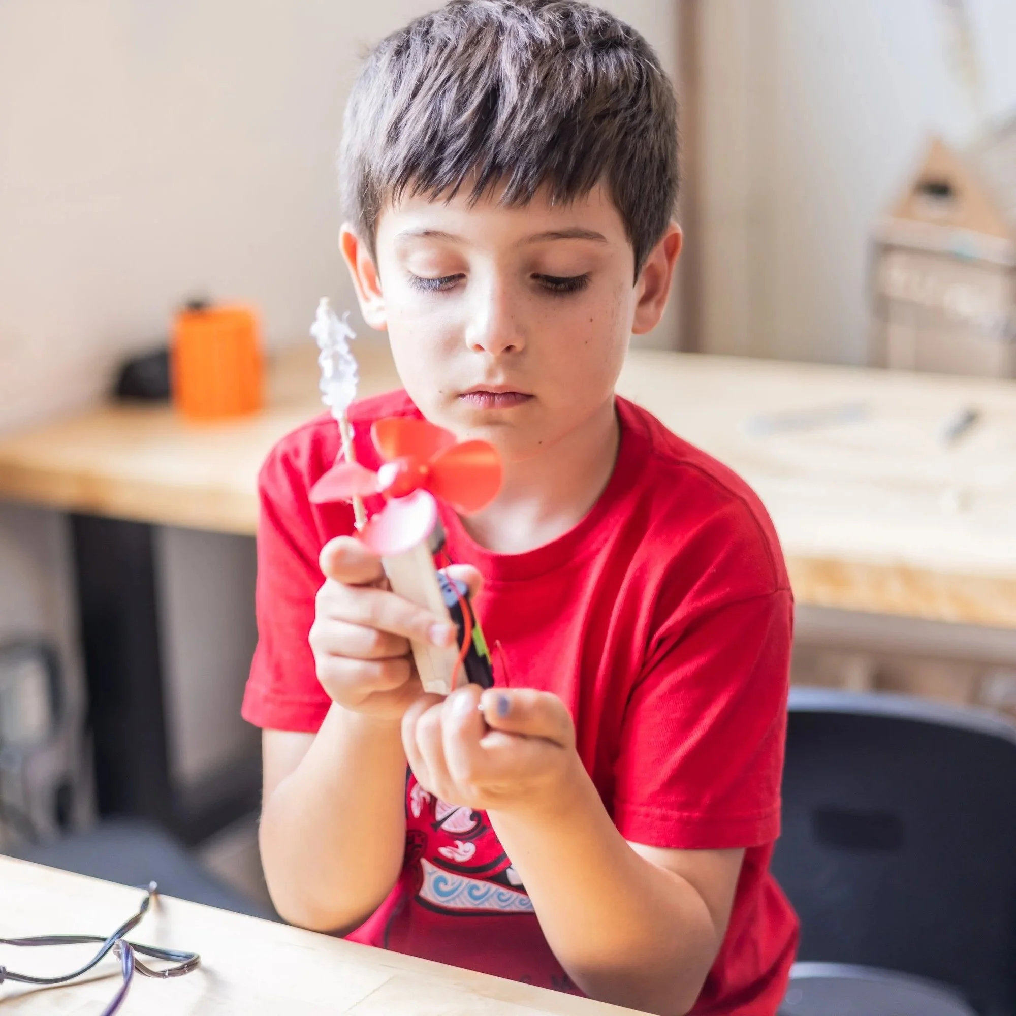 A kid holding a finished spinning project they built at Forge.