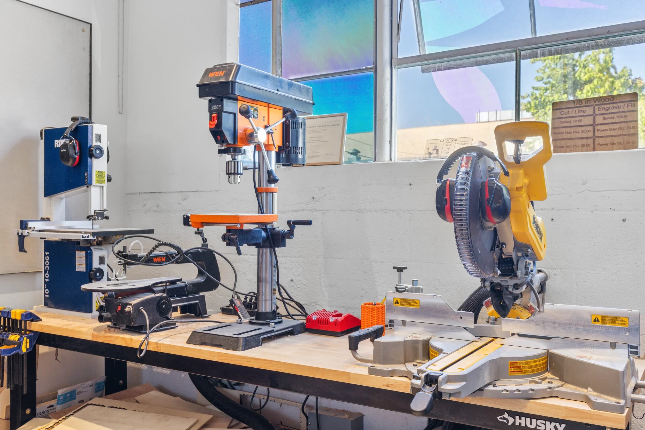 A miter saw and drill press on the Forge workshop floor.