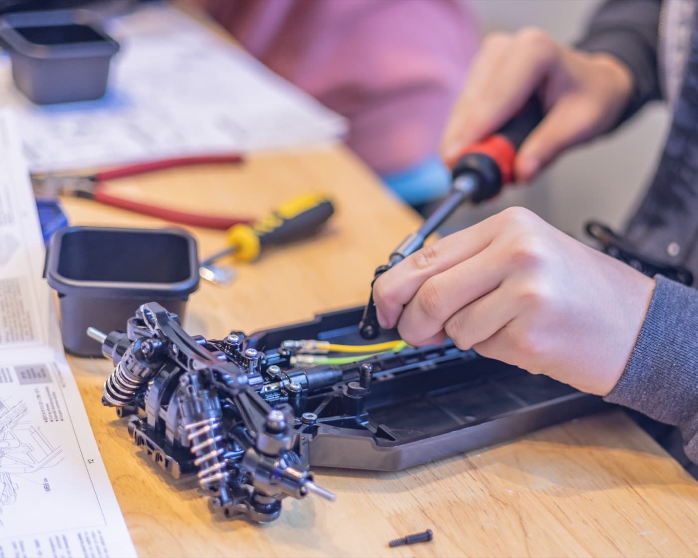 A camper's hands assembling the chassis of the RC car they built at Forge summer camp.