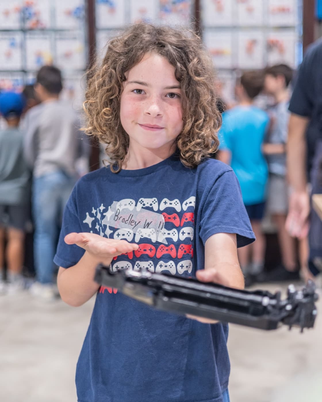A camper holding up the robotic arm he built at Forge summer camp.